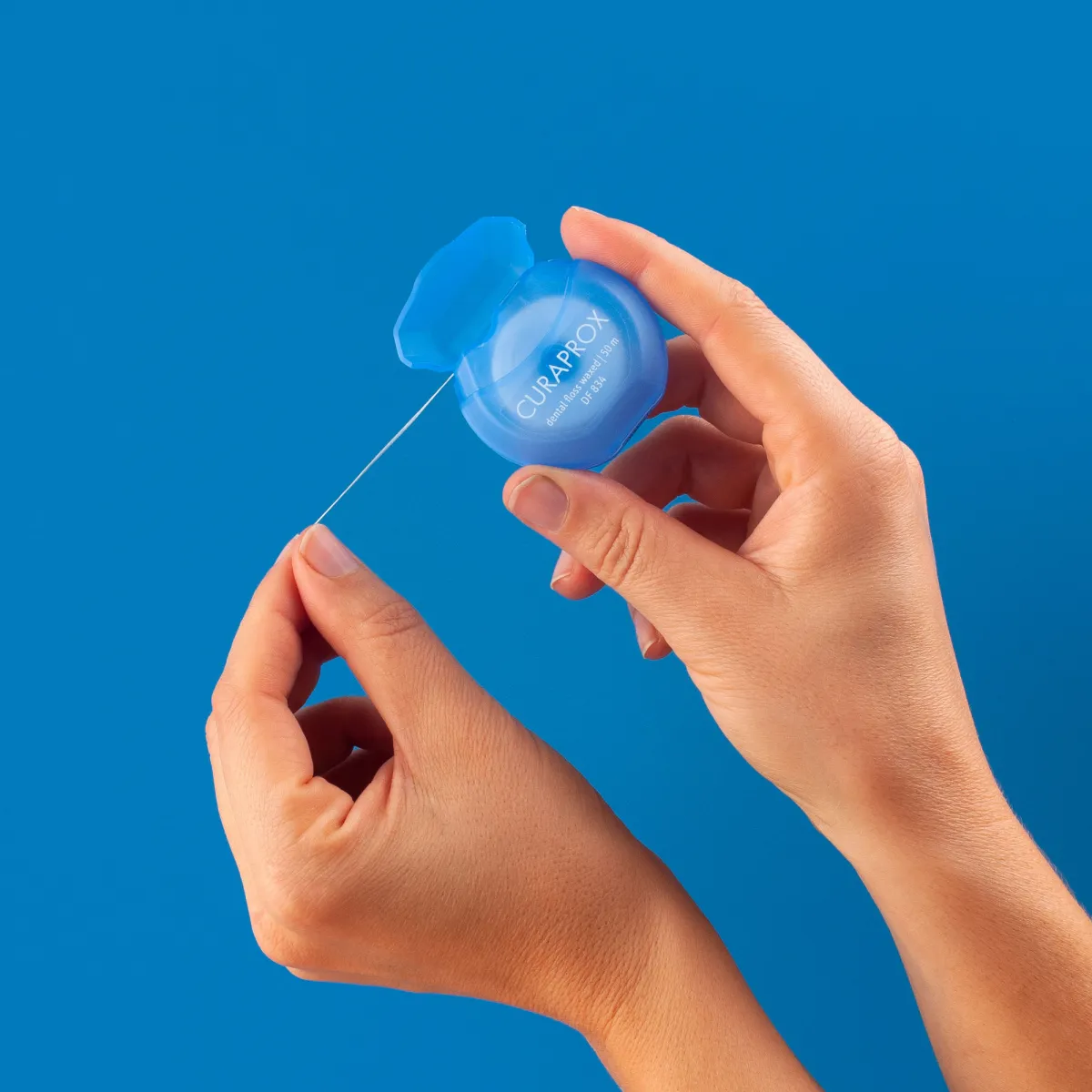 Hands pulling dental floss